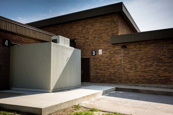 A grey walk-in cold storage unit attached to brick building