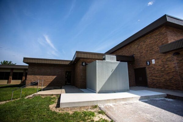 A grey walk-in Polar King freezer cooler attached to a brick building