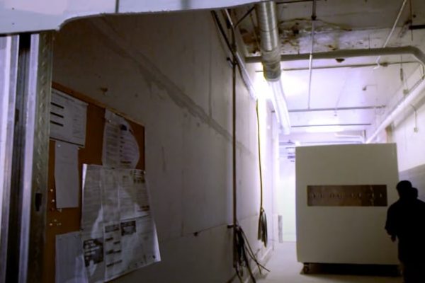 Small walk-in commercial refrigerator in a hallway