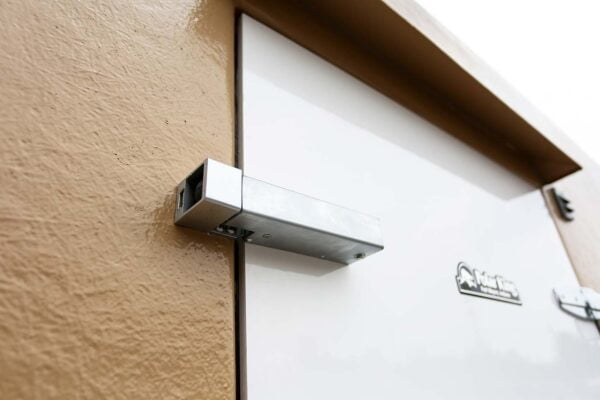 Close up of white walk-in cooler door with brown walls