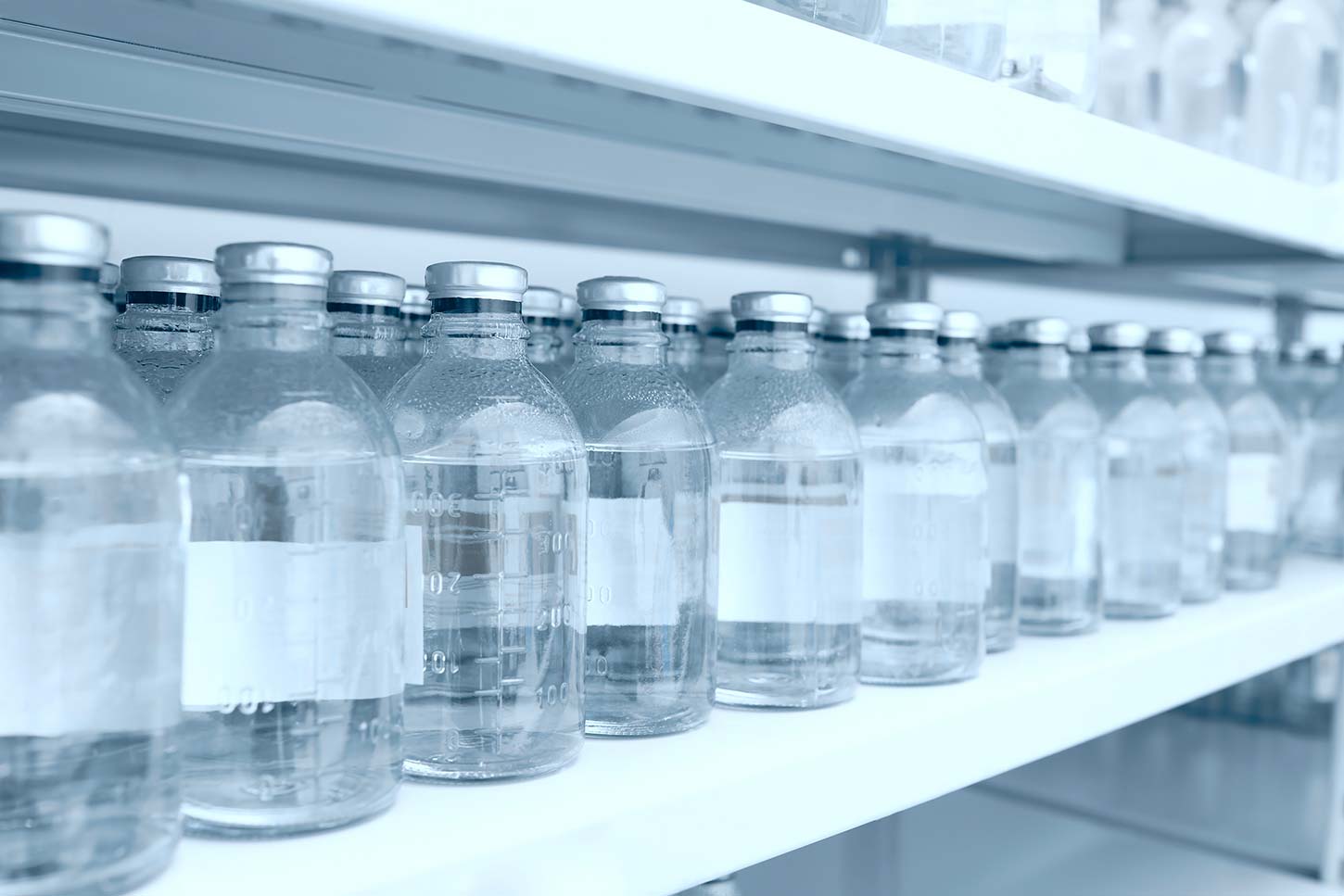 Containers with a clear liquid on white metal shelves
