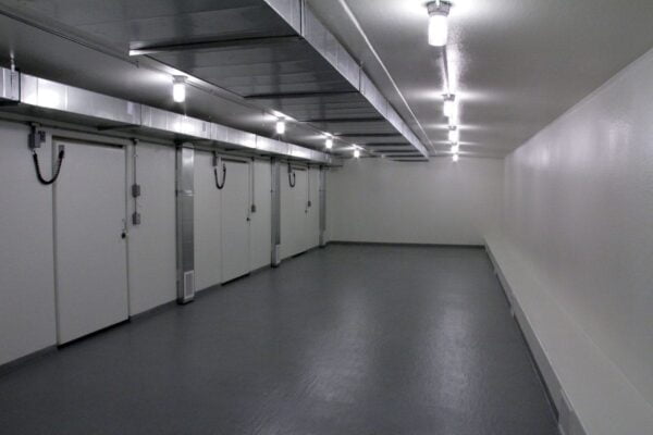Three walk-in cooler doors in a white room with grey floors