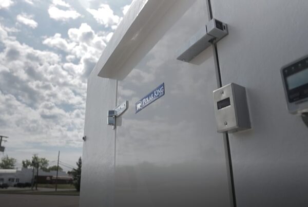 Ground view of the Polar King outdoor walkin cooler with a blue sky and clouds in the background