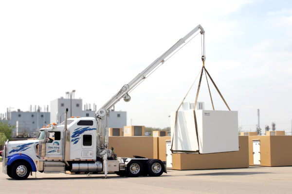 A crane on a semi truck lifting a custom cold room